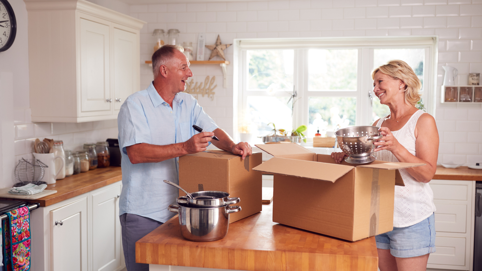 man and woman packing boxes in the kitchen