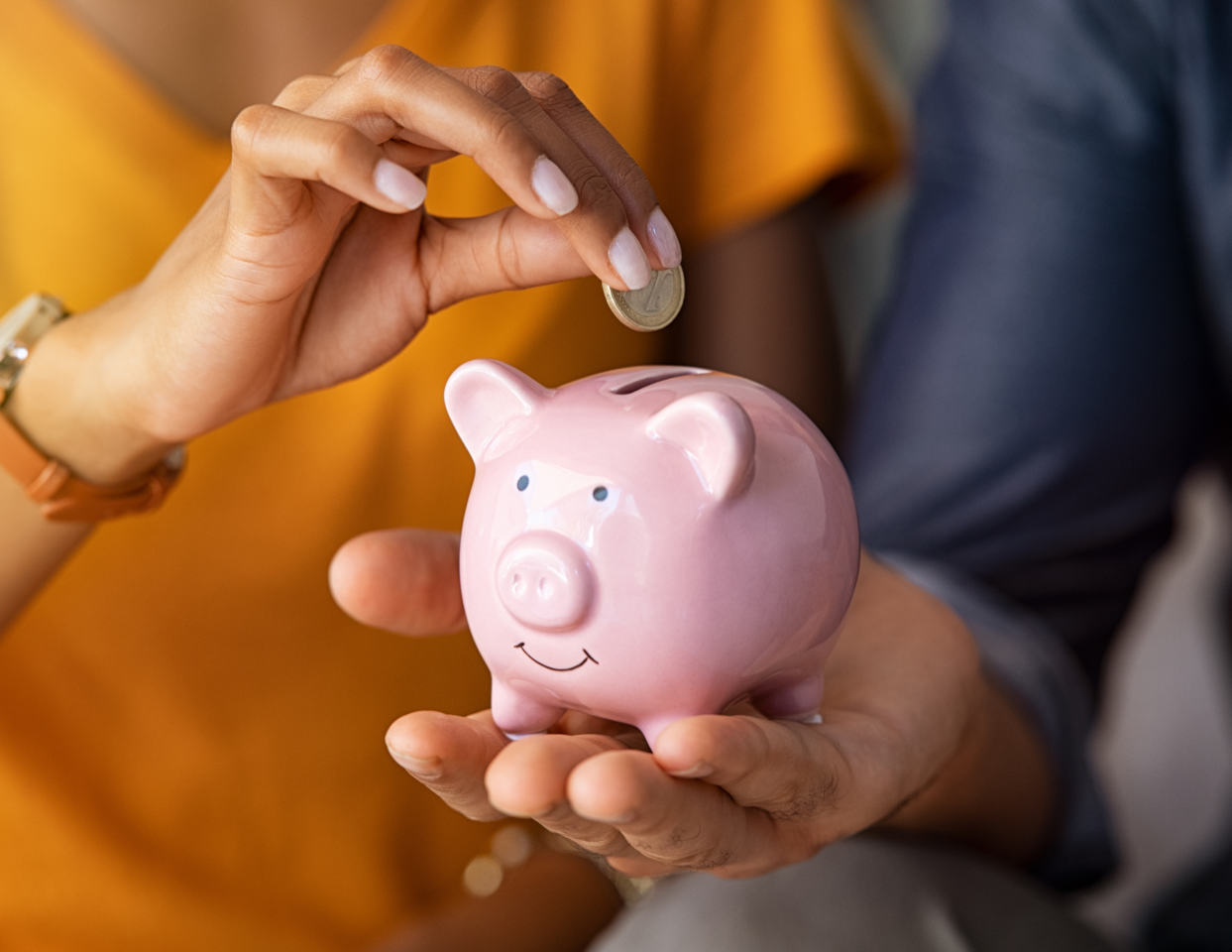 person putting money into piggy bank